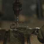 Detailed view of metal drilling process with shavings in workshop environment.